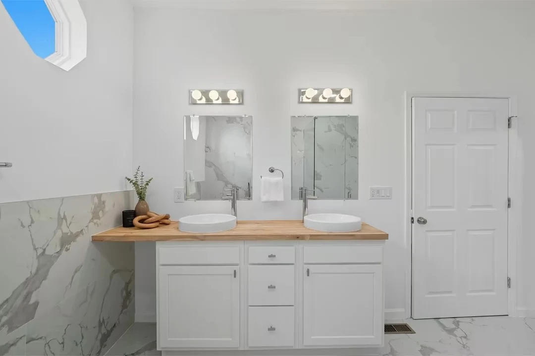 Vessel sinks, wood countertop and mirrored vanities