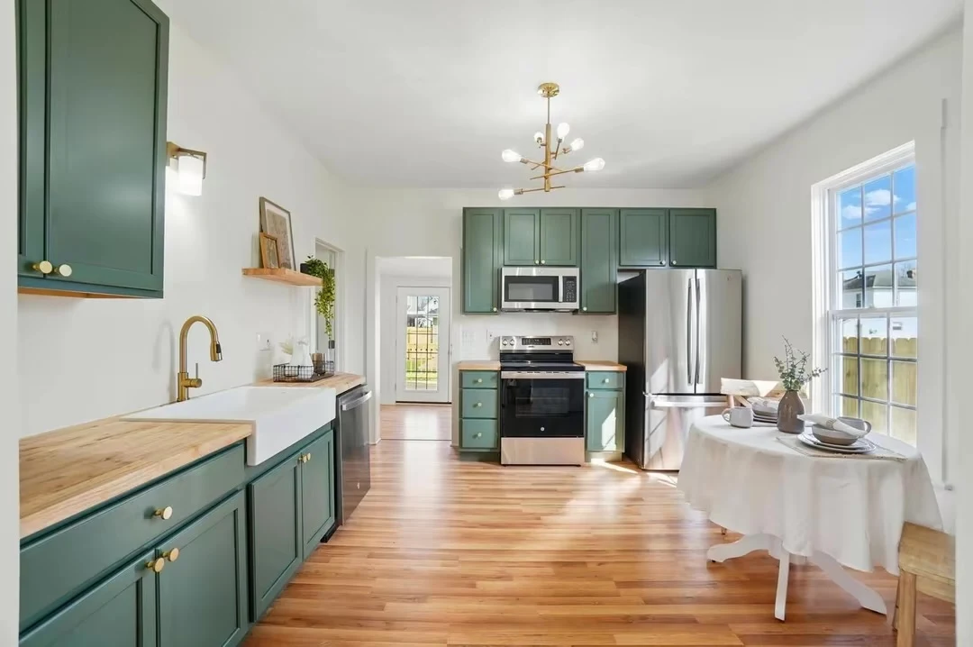 Green kitchen cabinetry with wood countertops, farmhouse sink and brass fixtures