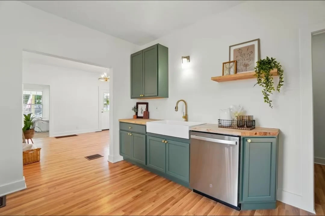 White farmhouse sink, brass faucet and green base cabinets