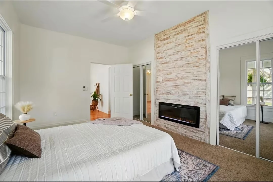 Bedroom with light wood accent wall and electric fireplace