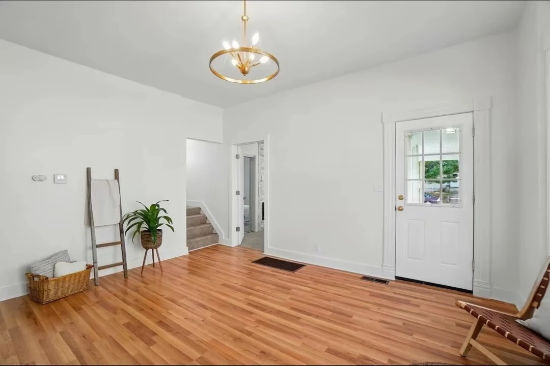 White entryway with wood flooring and brass pendant lighting